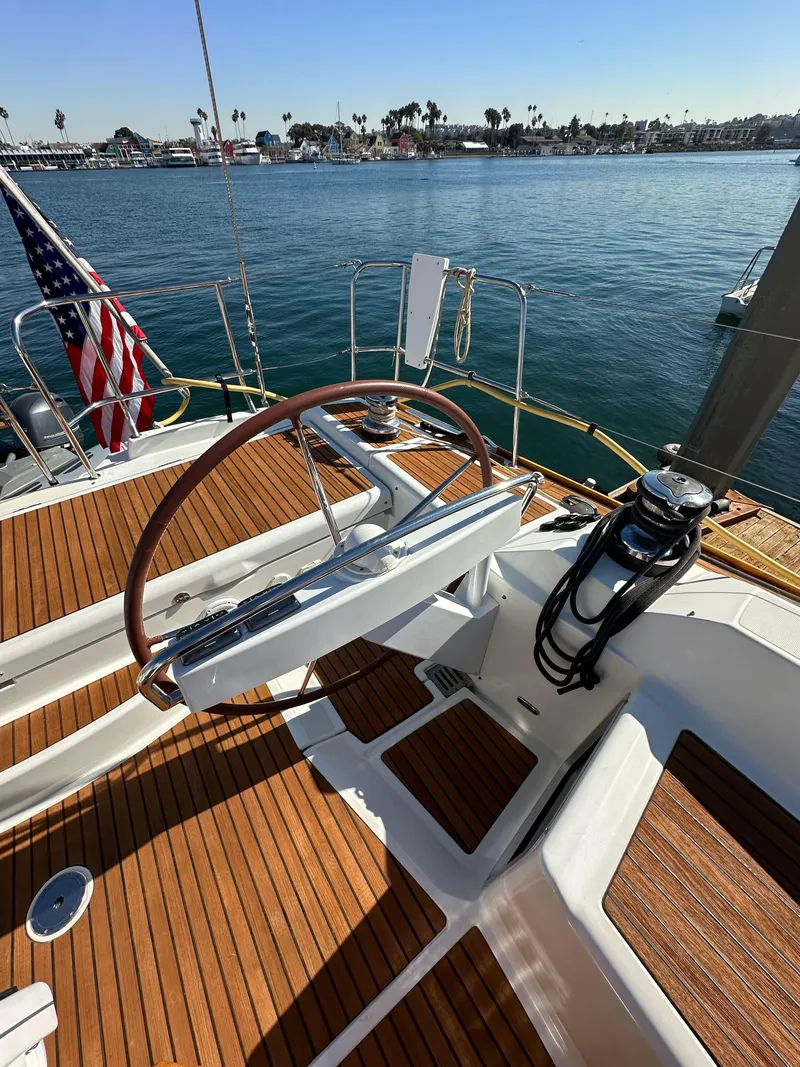 Slide: The Image of 2013 Jeanneau 57 sailboat deck with steering wheel, docked by calm waters. - 30