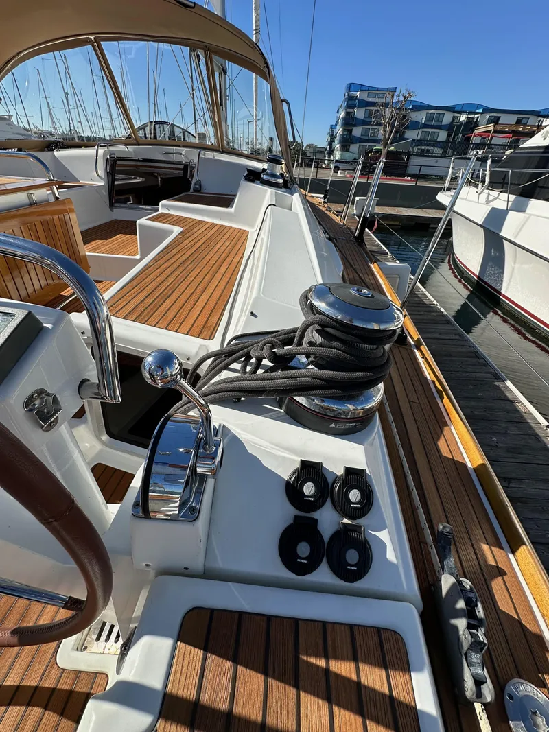 Slide: The Image of 2013 Jeanneau 57 sailboat deck with winches and teak finish in marina. - 44