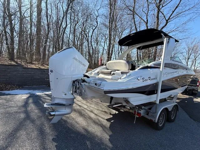 Slide: The Image of 2020 Crownline Eclipse E255 XS boat on trailer in wooded area. - 2