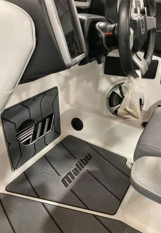 Slide: The Image of 2021 Malibu 23 LSV boat interior with steering wheel and branded floor mat. - 10