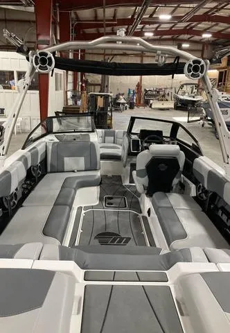 Slide: The Image of 2021 Malibu 23 LSV boat interior with gray seating in a warehouse setting. - 3