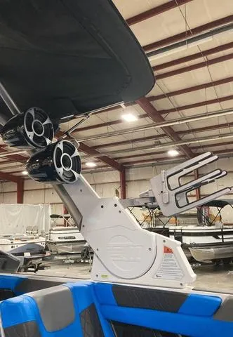 Slide: The Image of 2021 Malibu M240 boat interior with speakers and wakeboard rack in a warehouse. - 11