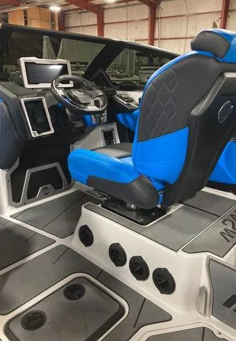 Slide: The Image of 2021 Malibu M240 boat interior with blue and black seating, modern dashboard, and steering wheel. - 7