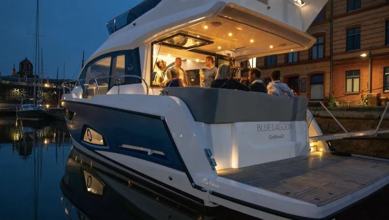 Slide: The Image of 2025 Sealine F430 yacht docked at night with people socializing onboard. - 12