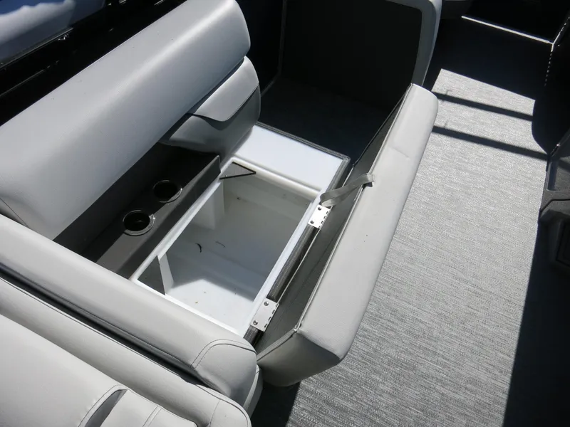 Slide: The Image of 2024 Godfrey Monaco 235SD boat interior with open storage compartment and cup holders. - 17