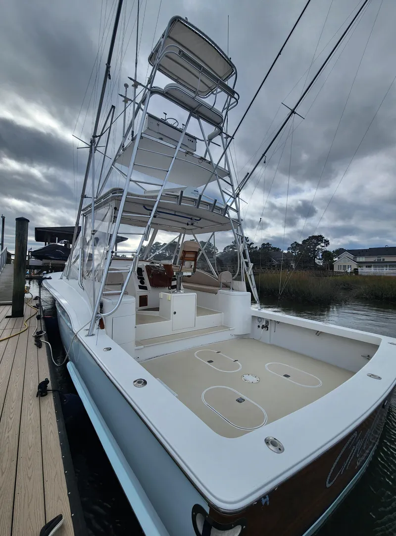 Slide: The Image of 1996 Jersey Devil boat docked, featuring a spacious deck and tall tower under cloudy skies. - 13