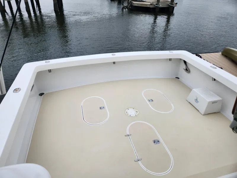 Slide: The Image of 1996 Jersey Devil boat deck with storage hatches, docked by calm water. - 15