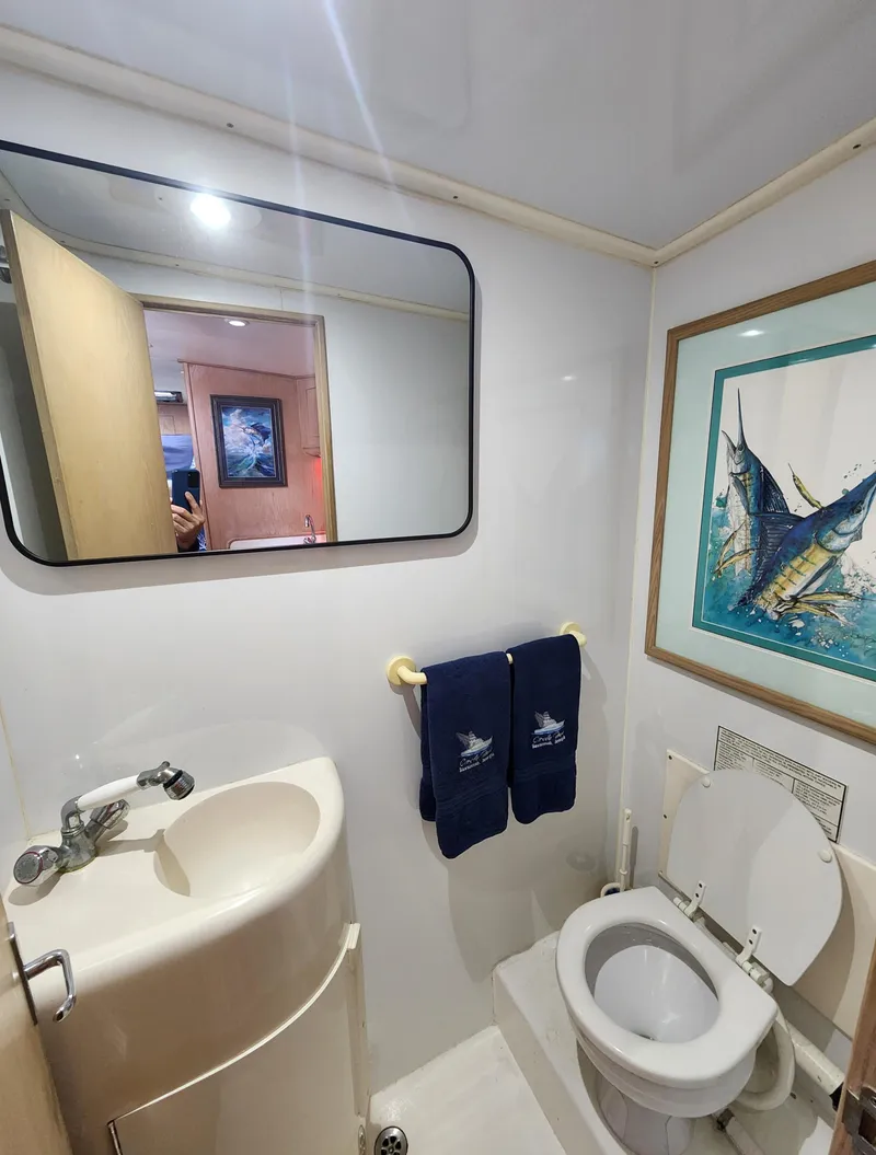 Slide: The Image of Compact bathroom in 1996 Jersey Devil boat with sink, toilet, mirror, and nautical-themed decor. - 23