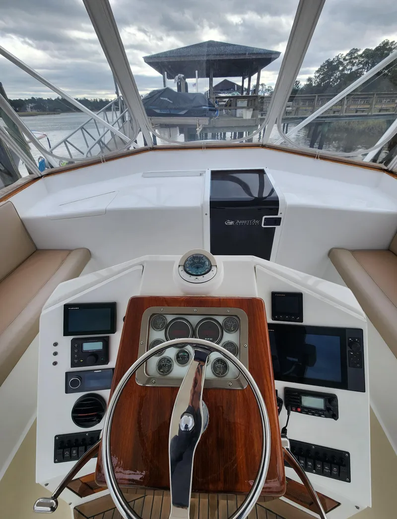 Slide: The Image of 1996 Jersey Devil boat helm with modern navigation equipment and scenic marina view. - 9