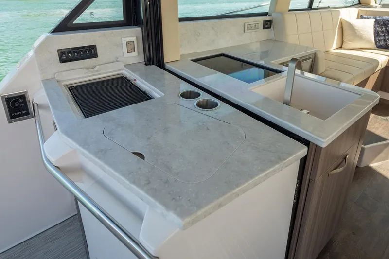 Slide: The Image of 2026 Regal 38 XO yacht interior with white seating, docked near other boats. - 13