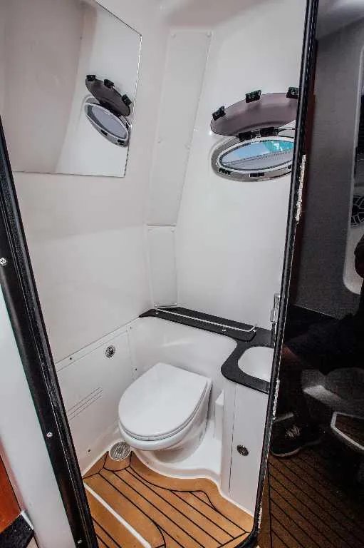 Slide: The Image of 2021 Caymas 401 CC boat bathroom with toilet, sink, and porthole window. - 17