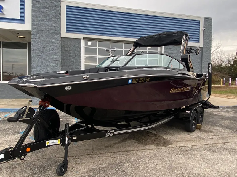 Slide: The Image of 2022 MasterCraft XT24 boat on trailer outside dealership. - 1