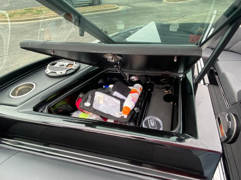Slide: The Image of Open storage compartment in 2022 MasterCraft XT24 boat with various items inside. - 22