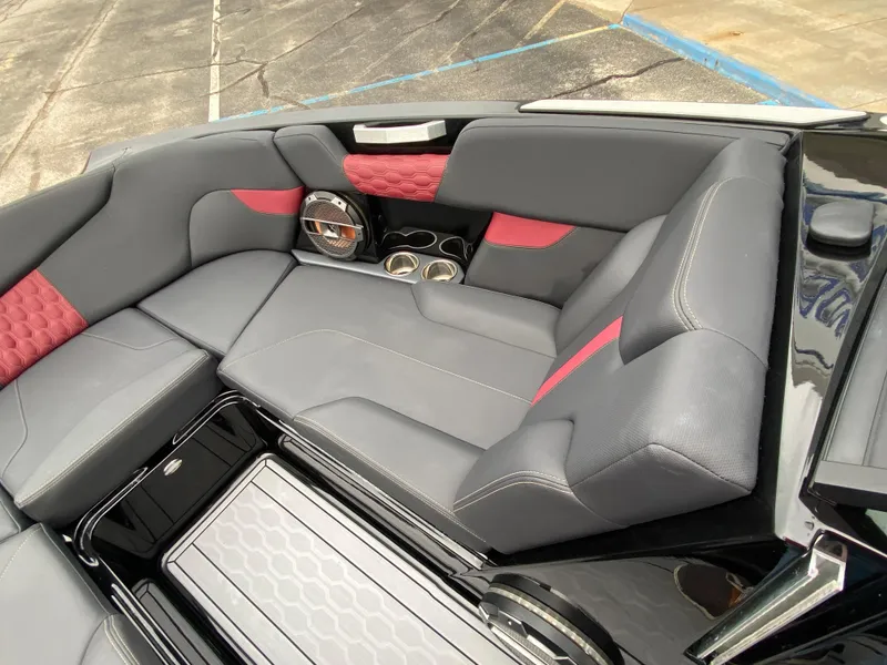 Slide: The Image of 2022 MasterCraft XT24 boat interior with gray and red seating, cup holders, and speaker. - 25