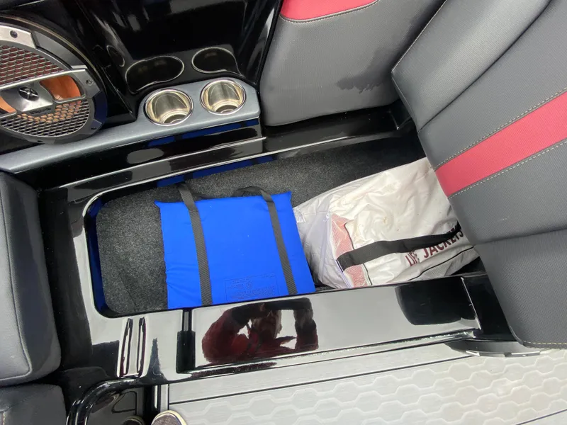 Slide: The Image of 2022 MasterCraft XT24 boat interior storage with blue bag and cup holders. - 28