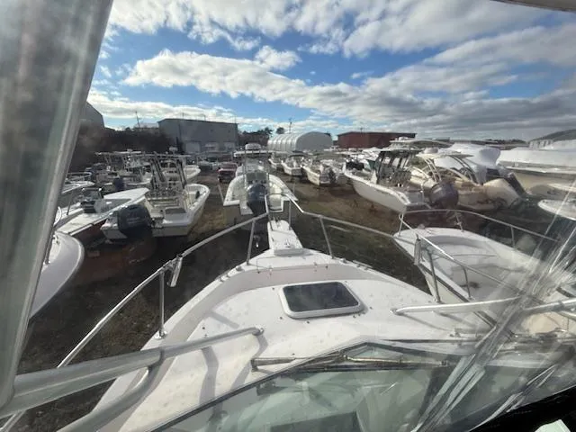 Slide: The Image of 2002 Grady-White 232 Gulfstream boat in a marina with other vessels under a cloudy sky. - 18