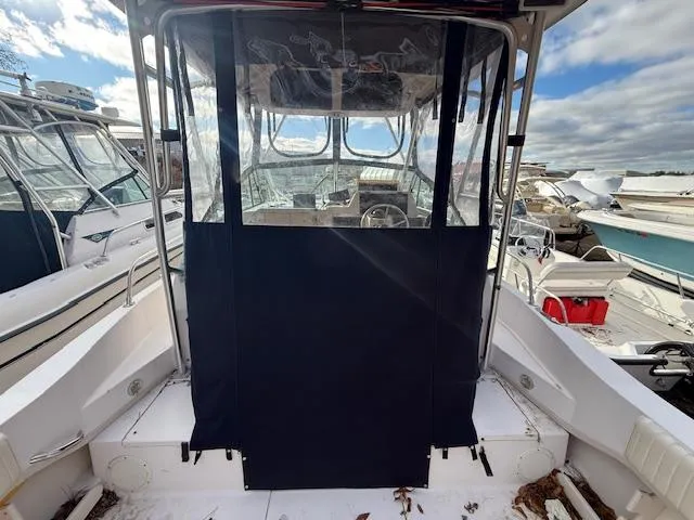 Slide: The Image of 2002 Grady-White 232 Gulfstream boat with covered cockpit, docked under cloudy sky. - 7