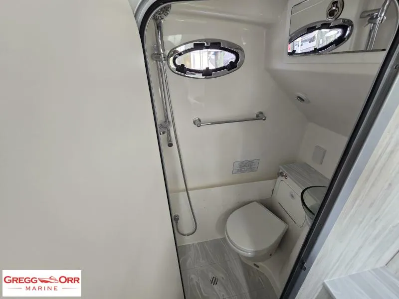 Slide: The Image of 2024 Regulator 37 boat bathroom with shower, toilet, and porthole window. - 23