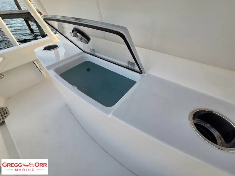 Slide: The Image of 2025 Regulator 26XO Crossover boat interior with open storage compartment and cup holder. - 11
