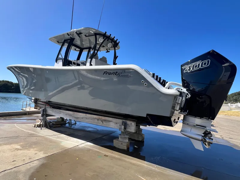 Slide: The Image of 2023 Front Runner 33 Center Console boat on a lift by the water. - 34