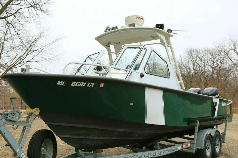 Slide: The Image of 2002 SeaArk 25 V Commander SAMA 1365 boat on trailer, green and white exterior. - 0