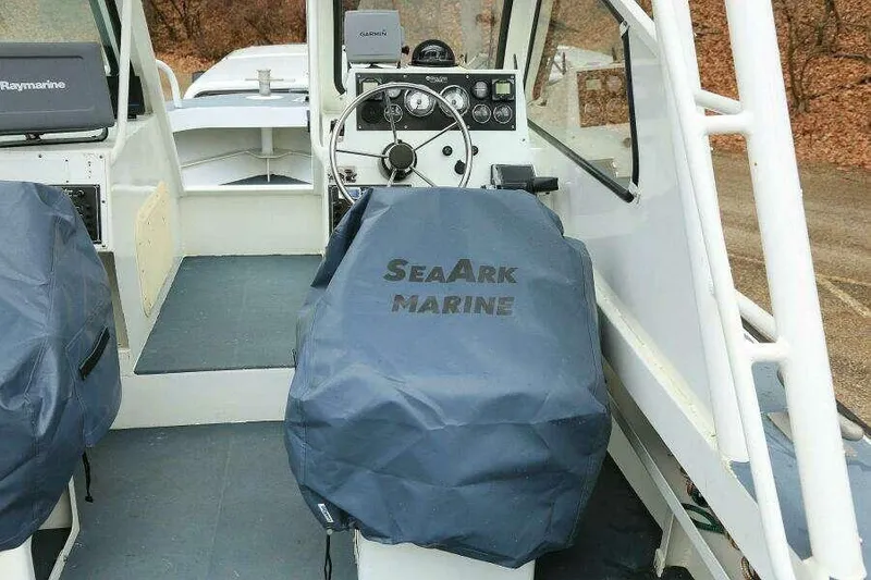 Slide: The Image of 2002 SeaArk 25 V Commander SAMA 1365 boat interior with covered seats and steering wheel. - 20