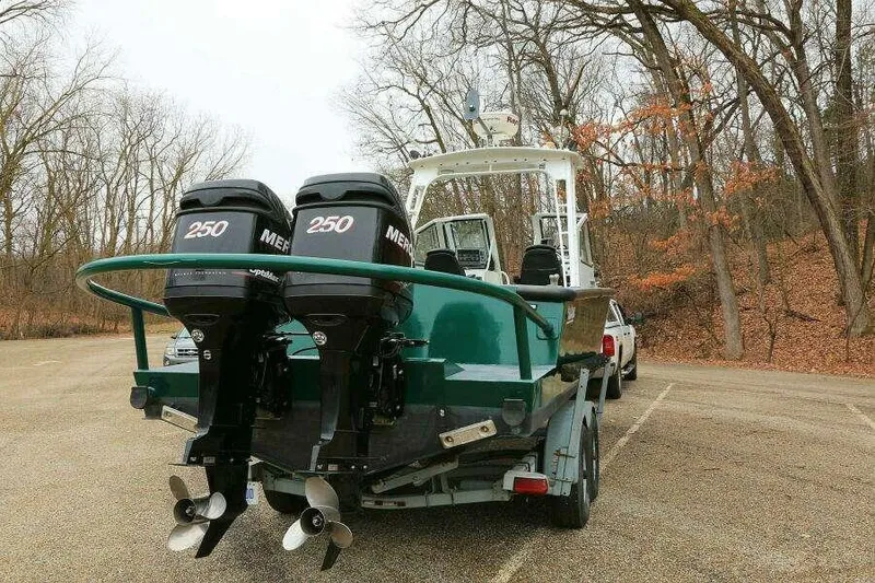 Slide: The Image of 2002 SeaArk 25 V Commander SAMA 1365 boat with dual 250 horsepower engines in a wooded parking area. - 3