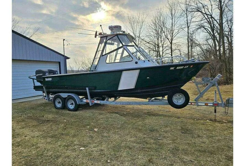 Slide: The Image of 2002 SeaArk 25 V Commander SAMA 1365 boat on trailer, parked near a garage. - 41