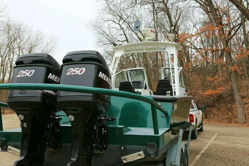 Slide: The Image of 2002 SeaArk 25 V Commander boat with dual Mercury 250 engines in a wooded parking area. - 43