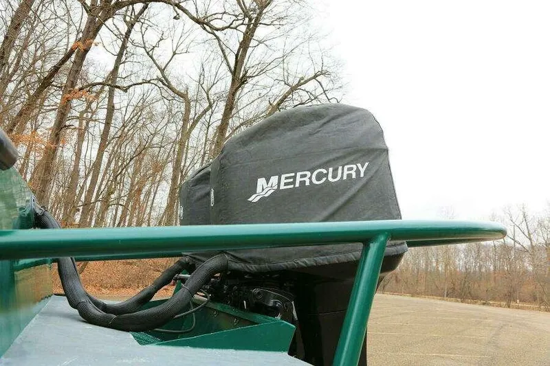 Slide: The Image of 2002 SeaArk 25 V Commander with Mercury engine cover, parked near leafless trees. - 46