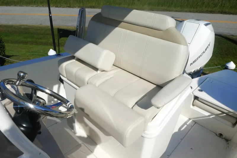 Slide: The Image of 2025 Boston Whaler 220 Dauntless boat interior with steering wheel and cushioned seating. - 11