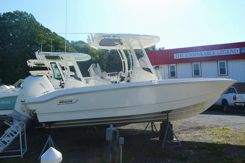 Slide: The Image of 2025 Boston Whaler 220 Dauntless boat displayed outdoors near dealership. - 2