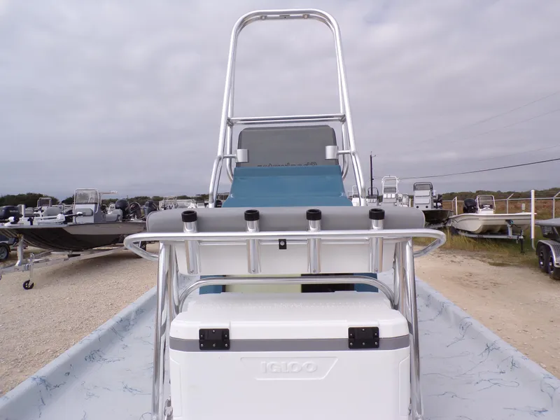 Slide: The Image of 2025 Shoalwater 19 CAT boat with cooler and rod holders, parked outdoors. - 16