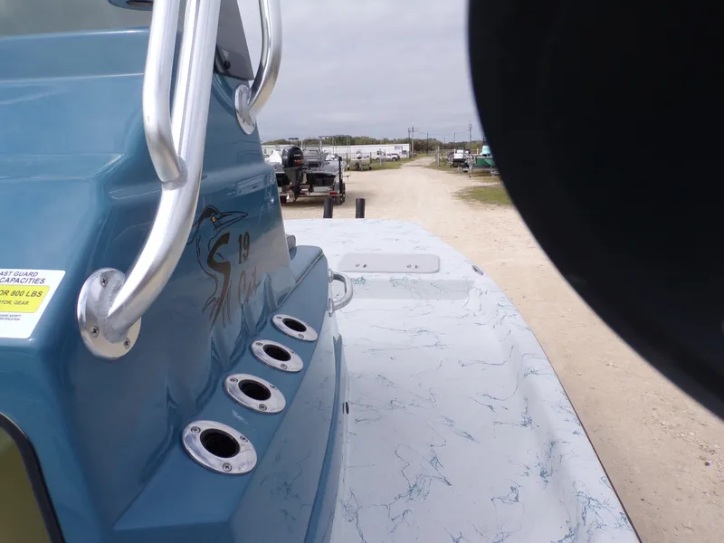 Slide: The Image of 2025 Shoalwater 19 CAT boat with blue exterior and rod holders, parked on a dirt road. - 23