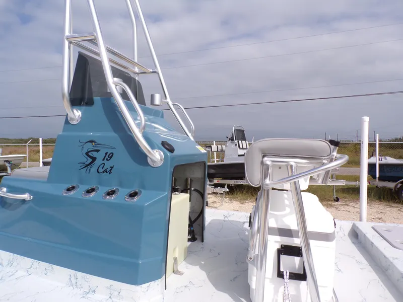 Slide: The Image of 2025 Shoalwater 19 CAT boat with blue console and seating, parked outdoors. - 29