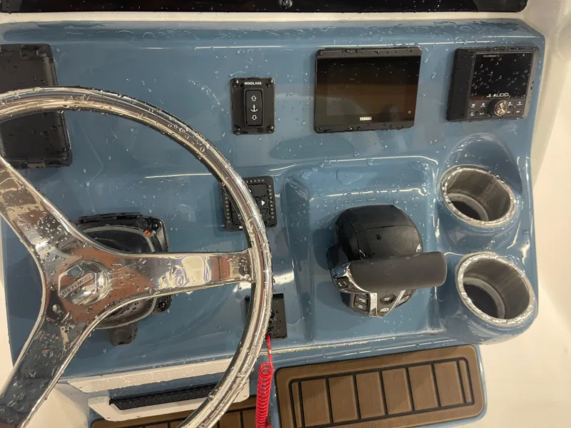 Slide: The Image of 2025 Tidewater 232LXF boat dashboard with steering wheel, controls, and cup holders. - 24