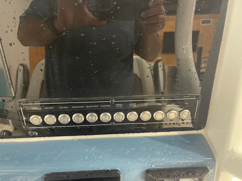 Slide: The Image of Control panel of 2025 Tidewater 232LXF boat with various switches and water droplets. - 28