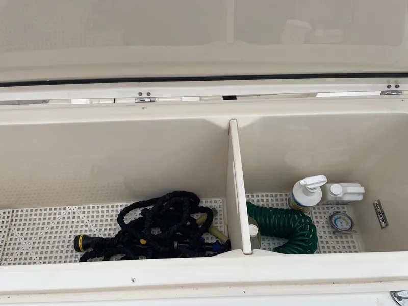 Slide: The Image of Storage compartment on 2019 Grady-White Canyon 336 boat with hose and cleaning supplies. - 14