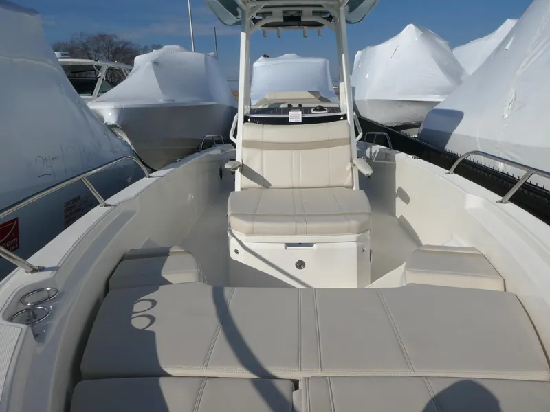 Slide: The Image of 2025 Boston Whaler 250 Dauntless boat interior with seating and console, docked outdoors. - 5