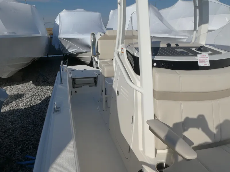Slide: The Image of 2025 Boston Whaler 250 Dauntless boat, side view, parked on gravel with covered boats nearby. - 8