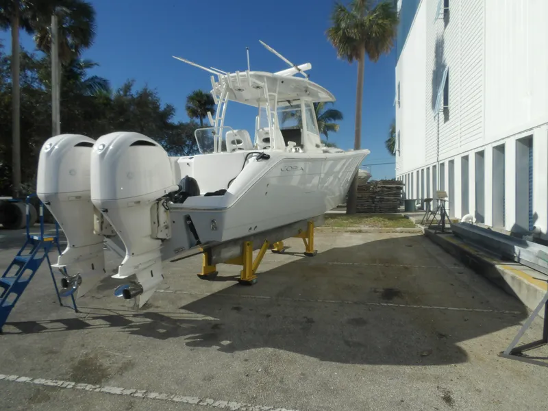 Slide: The Image of 2020 Cobia 320 Center Console boat with dual engines on a dockside platform. - 11