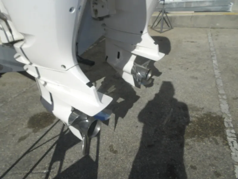 Slide: The Image of Twin outboard motors on a 2020 Cobia 320 Center Console boat, parked on concrete. - 15