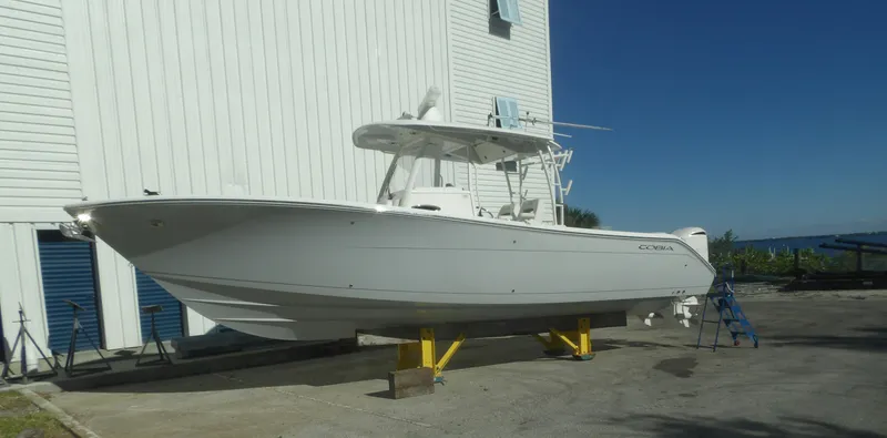 Slide: The Image of 2020 Cobia 320 Center Console boat on dry dock near a white building. - 2