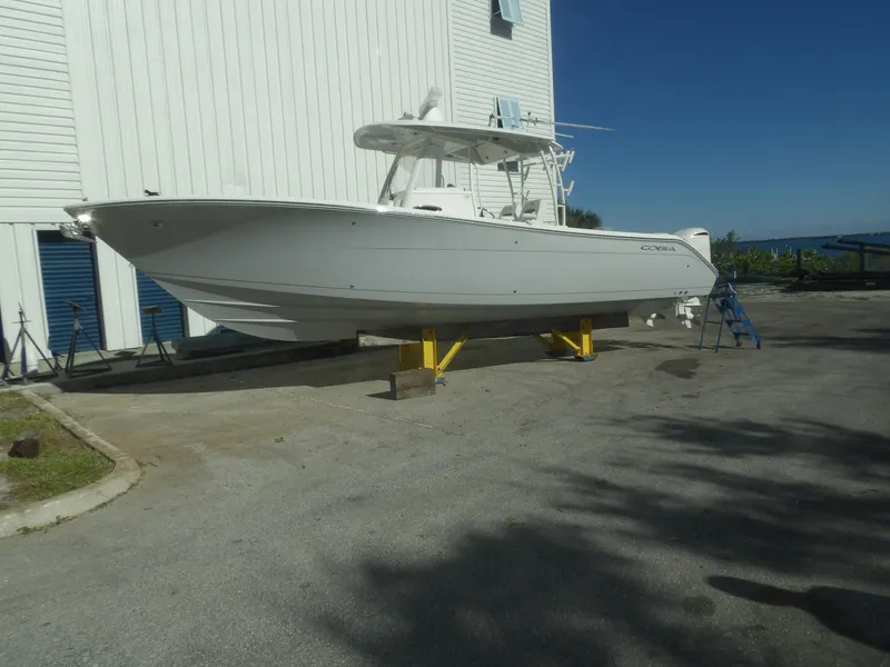 Slide: The Image of 2020 Cobia 320 Center Console boat on stands, near a white building, under clear blue sky. - 4