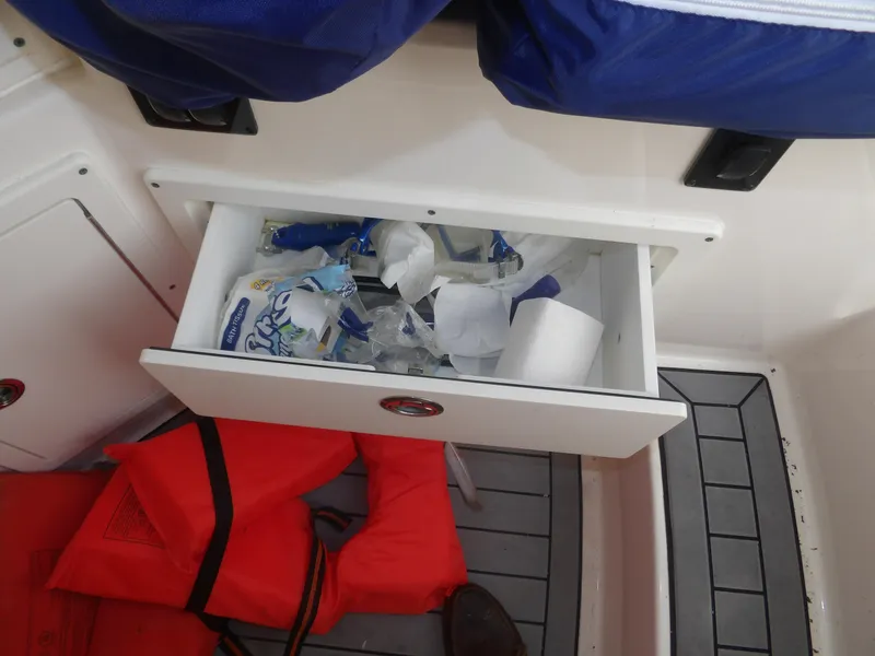 Slide: The Image of Open drawer on 2020 Cobia 320 Center Console boat with supplies and life jackets. - 41