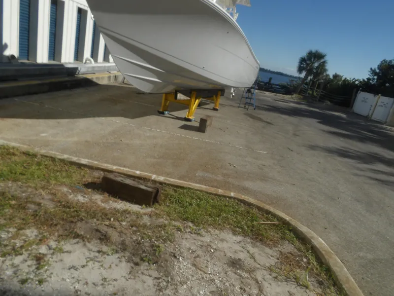 Slide: The Image of 2020 Cobia 320 Center Console boat on stands, near waterfront storage area. - 6