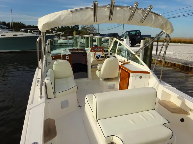Slide: The Image of 2008 Hunt Yachts Harrier 25 with white seating and canopy, docked by the water. - 13