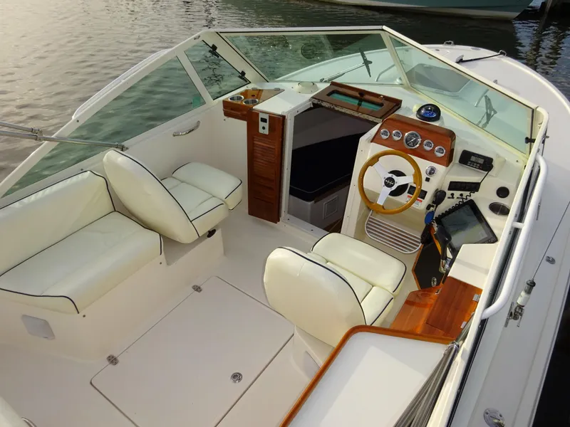 Slide: The Image of 2008 Hunt Yachts Harrier 25 interior with white seating and wooden dashboard, docked on calm water. - 17