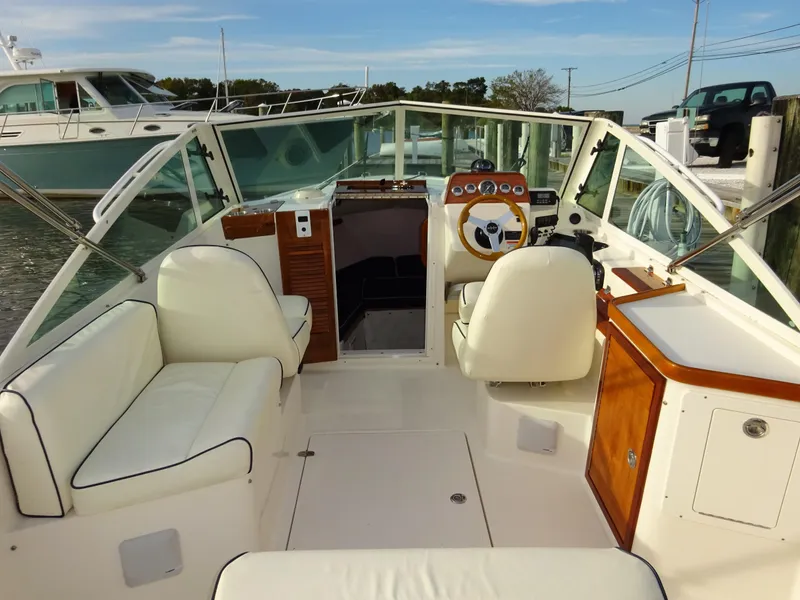 Slide: The Image of 2008 Hunt Yachts Harrier 25 interior with white seating and wooden accents, docked in a marina. - 2