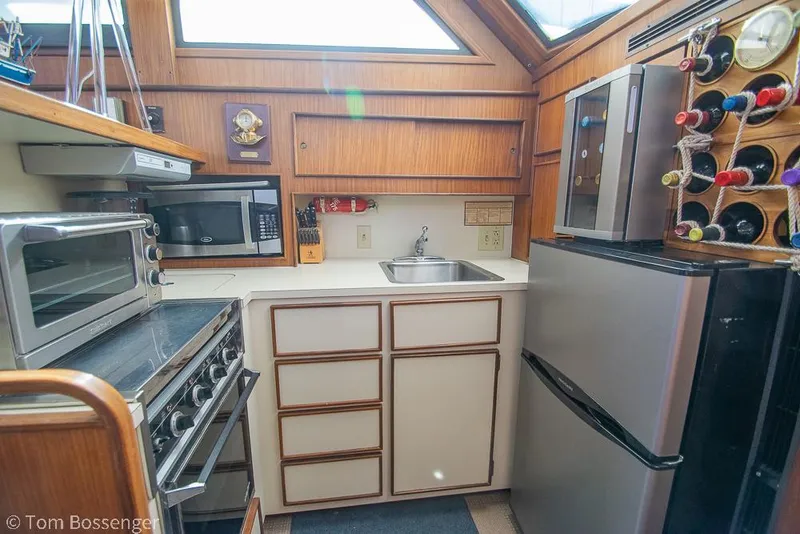 Slide: The Image of 1986 Hatteras 43 Motor Yacht kitchen with appliances, wine rack, and wood paneling. - 19